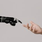 A human hand reaching to touch a bionic prosthetic hand on a white background.