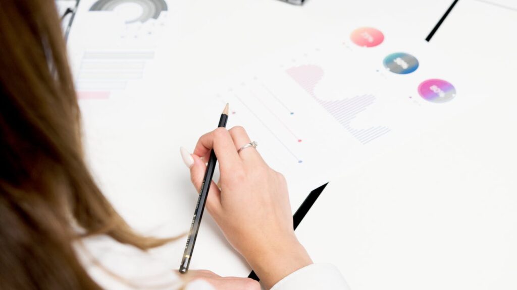 A woman reviews colorful financial charts with a pencil, focusing on growth and data analysis.